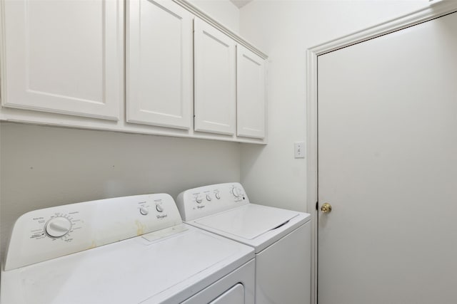 clothes washing area with cabinets and washing machine and clothes dryer