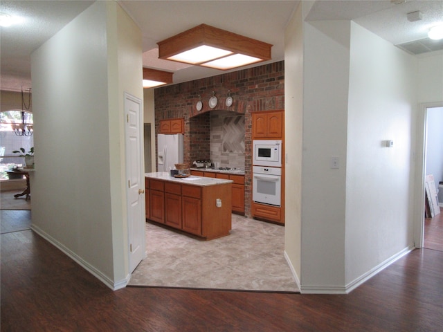 kitchen featuring brick wall, pendant lighting, white appliances, a kitchen island, and light wood-type flooring