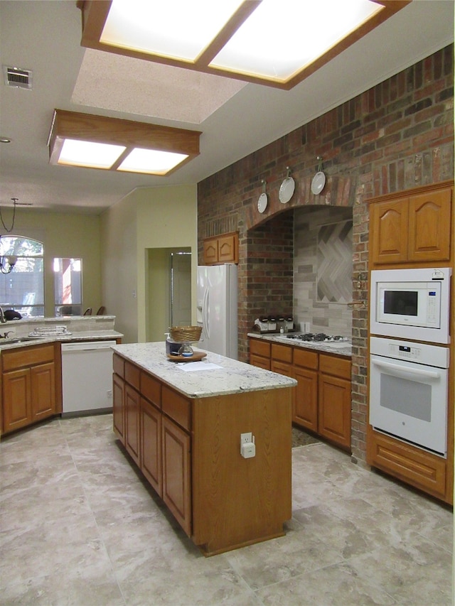 kitchen with brick wall, white appliances, sink, pendant lighting, and a center island