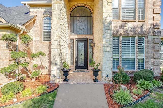 doorway to property with roof with shingles and brick siding