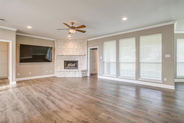 unfurnished living room featuring a ceiling fan, wood finished floors, crown molding, and a stone fireplace