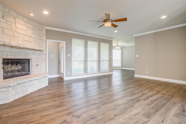 unfurnished living room with baseboards, ceiling fan, wood finished floors, crown molding, and a stone fireplace