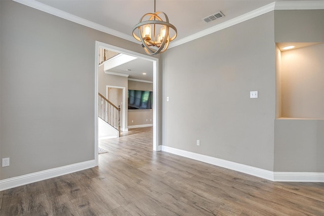 unfurnished room featuring baseboards, ornamental molding, wood finished floors, stairs, and a notable chandelier