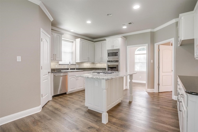 kitchen with light wood-style flooring, visible vents, white cabinetry, appliances with stainless steel finishes, and a center island