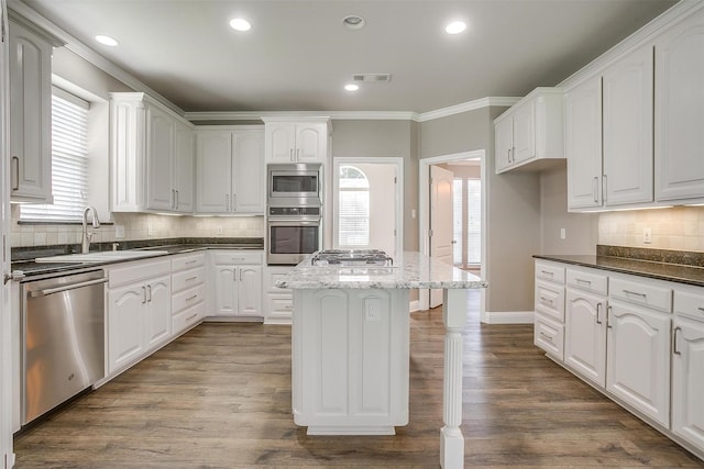 kitchen featuring stainless steel appliances, white cabinetry, a sink, and dark stone countertops