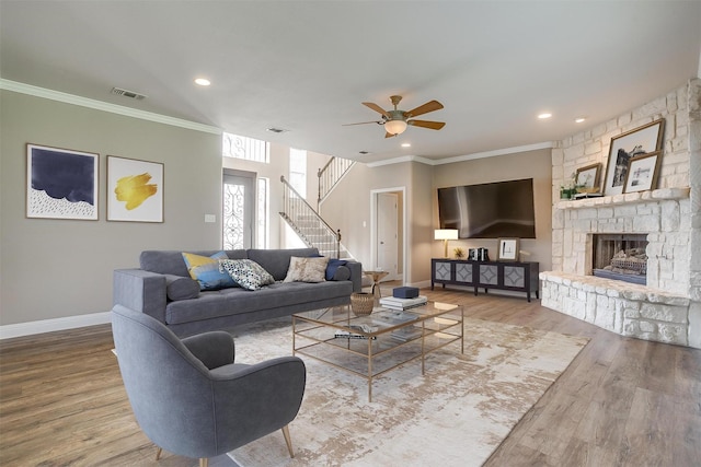 living room featuring a fireplace, baseboards, crown molding, and wood finished floors