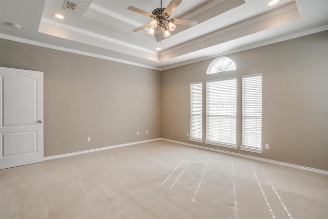 spare room featuring a raised ceiling, light colored carpet, visible vents, ornamental molding, and baseboards