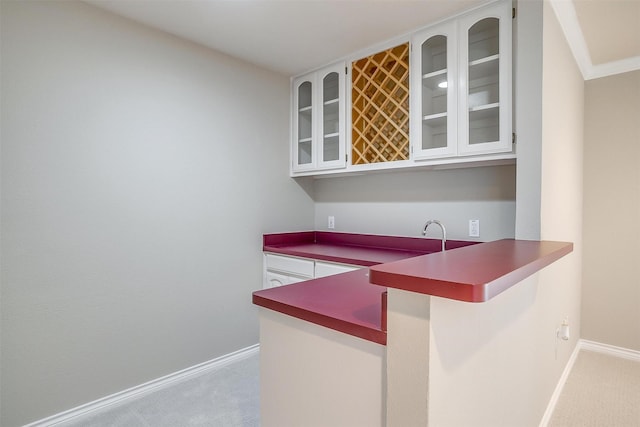 bar featuring baseboards, wet bar, and light colored carpet