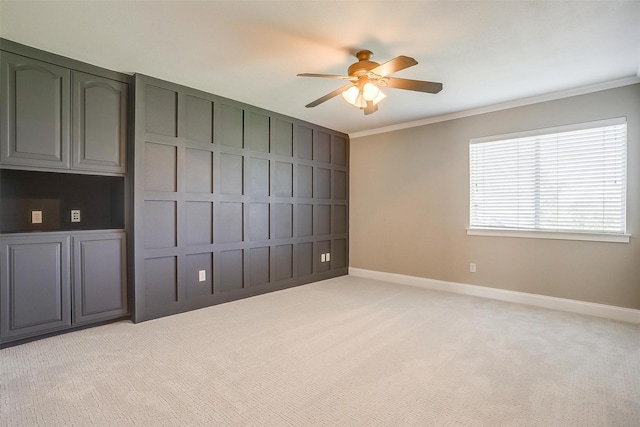 unfurnished bedroom featuring light carpet, crown molding, baseboards, and ceiling fan