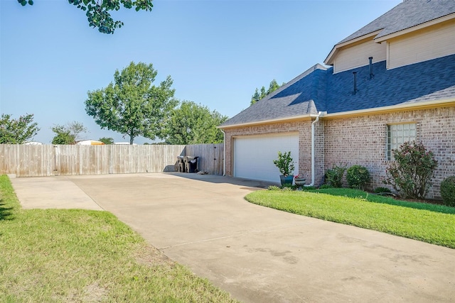 view of property exterior featuring brick siding, a shingled roof, fence, a garage, and driveway