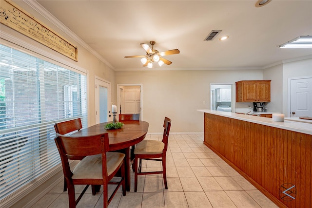 tiled dining space featuring washer / clothes dryer, ceiling fan, and ornamental molding