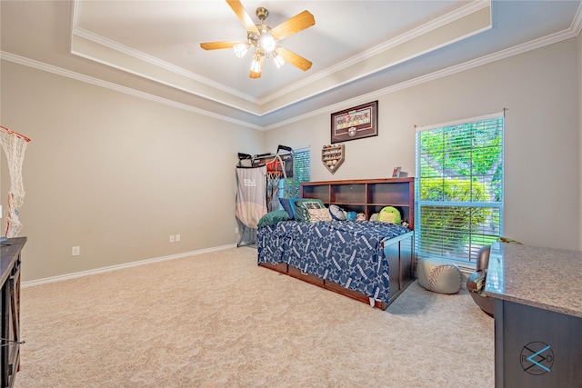 carpeted bedroom featuring a tray ceiling, ceiling fan, and crown molding