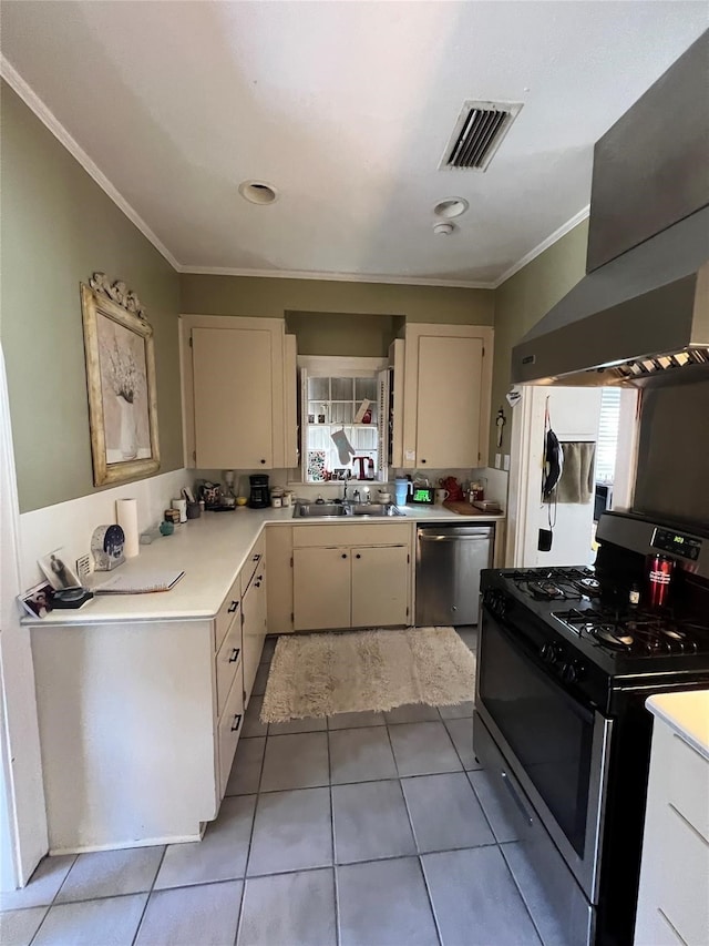 kitchen featuring wall chimney range hood, gas stove, stainless steel dishwasher, sink, and light tile flooring