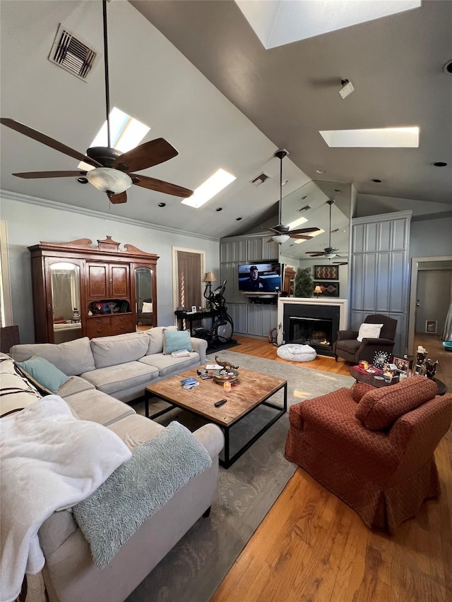 living room featuring vaulted ceiling with skylight, ceiling fan, and hardwood / wood-style floors