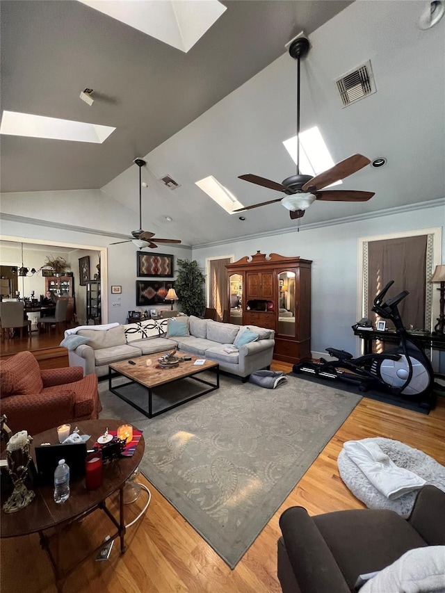 living room with ceiling fan, hardwood / wood-style flooring, and vaulted ceiling with skylight