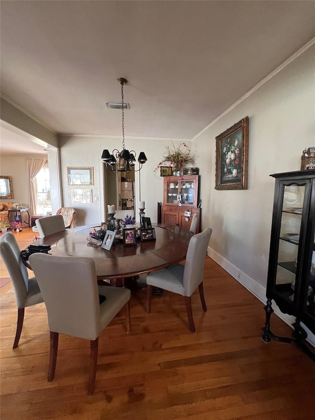 dining space with ornamental molding, an inviting chandelier, and hardwood / wood-style floors