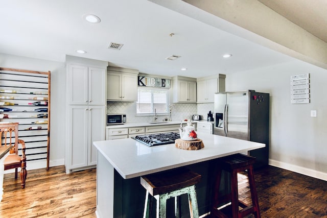 kitchen with stainless steel appliances, a breakfast bar, a sink, light wood-style floors, and tasteful backsplash