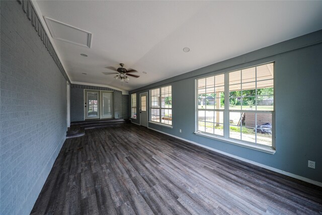 spare room featuring brick wall, ceiling fan, lofted ceiling, and dark wood-type flooring