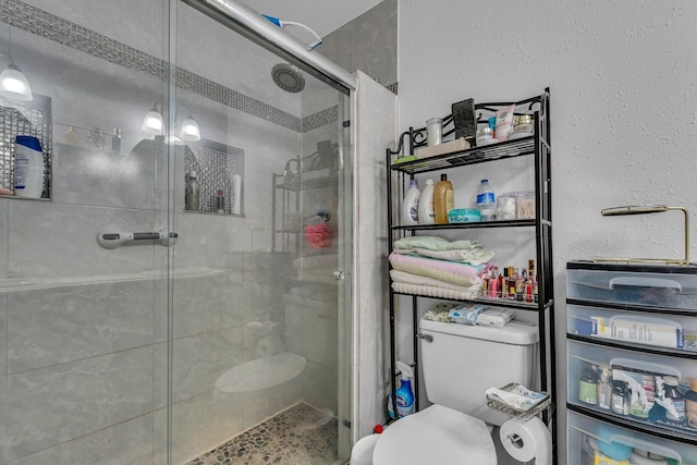 bathroom featuring toilet and a shower with shower door