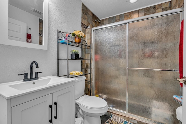 bathroom featuring a textured ceiling, vanity, toilet, and walk in shower