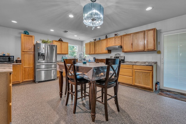 kitchen with decorative light fixtures, stainless steel appliances, light carpet, and an inviting chandelier