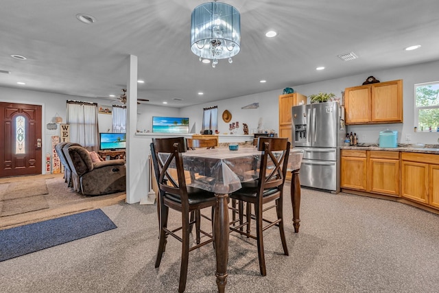 carpeted dining space featuring ceiling fan with notable chandelier