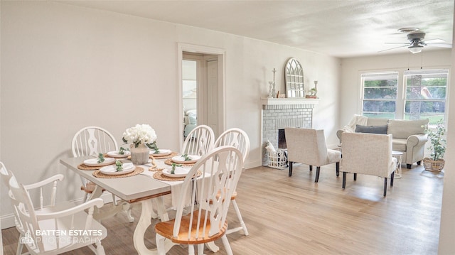 dining space with light hardwood / wood-style floors, ceiling fan, and a fireplace