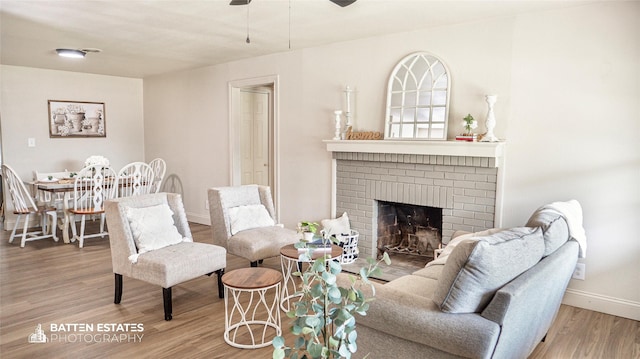 living room with ceiling fan, a fireplace, and hardwood / wood-style flooring