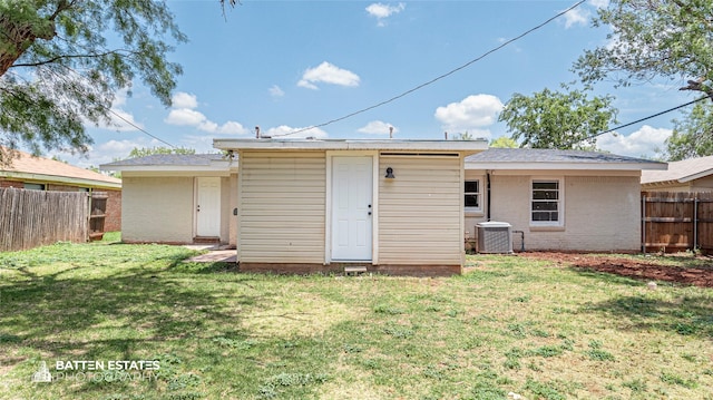 rear view of property featuring central AC and a lawn