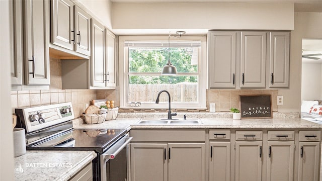 kitchen featuring backsplash, electric range, sink, light stone countertops, and gray cabinetry