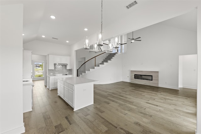 kitchen with a kitchen island, white cabinetry, high vaulted ceiling, hanging light fixtures, and light hardwood / wood-style floors