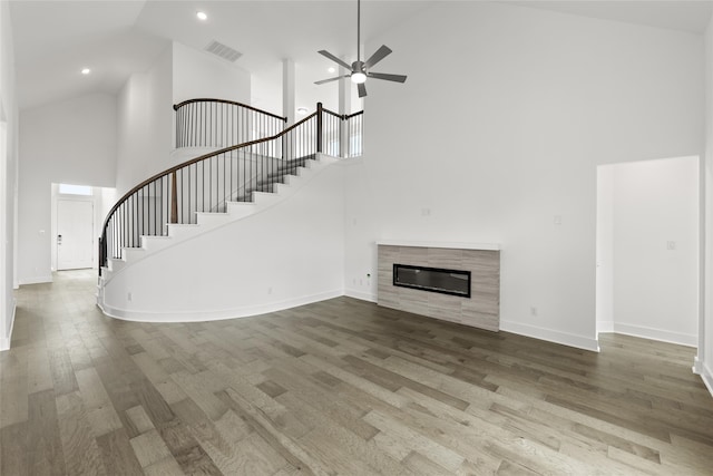 unfurnished living room featuring high vaulted ceiling, wood-type flooring, a tile fireplace, and ceiling fan