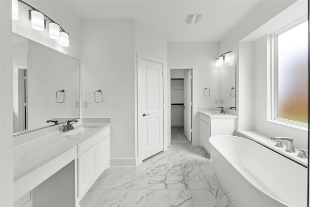 1727 Newport Dr, Cedar Hill, TX 75104 - bathroom with marble look tile flooring, a freestanding bath, baseboards, two vanities, and a spacious closet