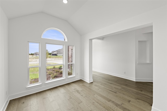 spare room with hardwood / wood-style floors, a healthy amount of sunlight, and vaulted ceiling