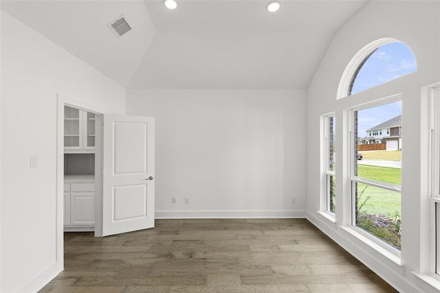 empty room featuring wood-type flooring and vaulted ceiling