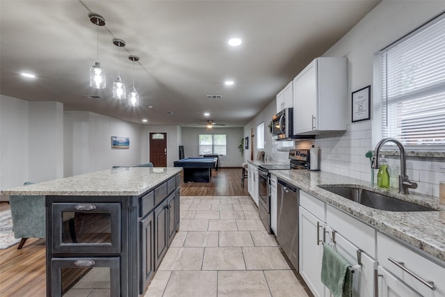 kitchen with billiards, sink, white cabinetry, pendant lighting, and stainless steel appliances