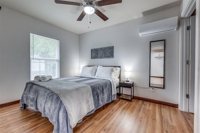 bedroom featuring a wall unit AC, ceiling fan, and light wood-type flooring