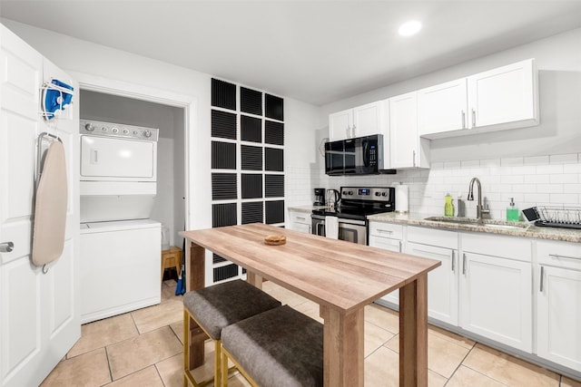 kitchen featuring electric stove, stacked washer and dryer, sink, white cabinetry, and tasteful backsplash