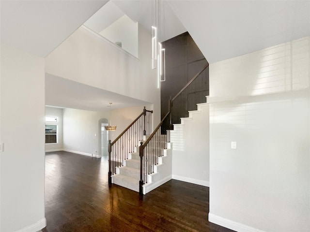 stairs featuring a notable chandelier, a towering ceiling, and hardwood / wood-style flooring