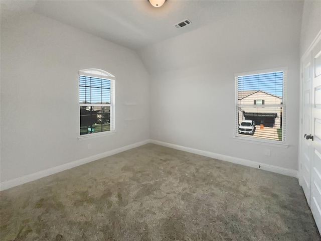 carpeted empty room featuring vaulted ceiling