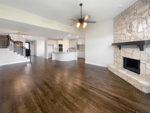 unfurnished living room with sink, dark hardwood / wood-style flooring, a fireplace, and ceiling fan