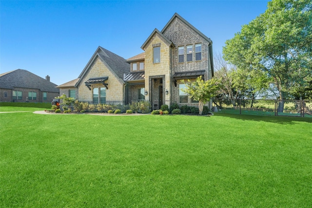 view of front of house featuring a standing seam roof, metal roof, fence, and a front lawn