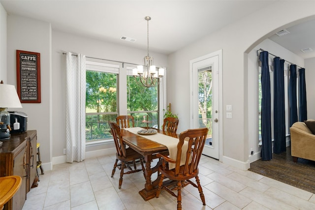 dining area with arched walkways, light tile patterned floors, visible vents, an inviting chandelier, and baseboards