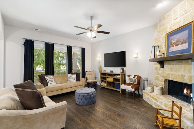 living room with a ceiling fan, a fireplace, visible vents, and dark wood-style flooring