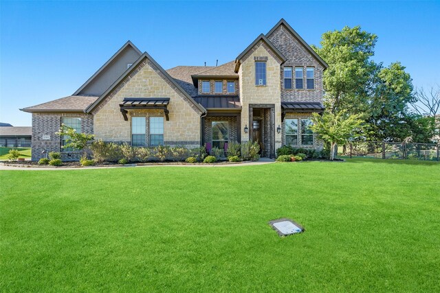 view of front of property with metal roof, fence, stone siding, a standing seam roof, and a front yard