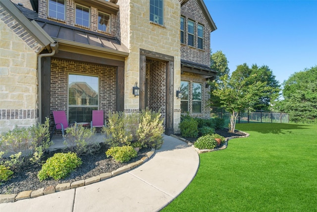 doorway to property with a lawn, stone siding, metal roof, a standing seam roof, and brick siding