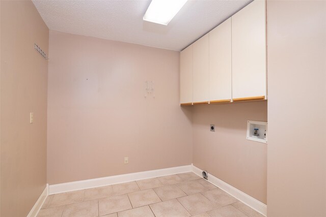 clothes washing area featuring hookup for a washing machine, light tile patterned floors, cabinets, and a textured ceiling