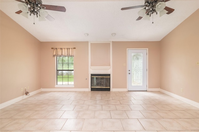 unfurnished living room with ceiling fan, light tile patterned floors, and a textured ceiling