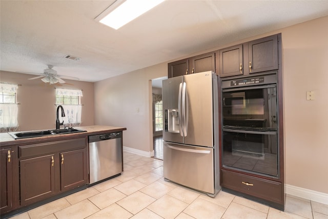 kitchen featuring sink, ceiling fan, a textured ceiling, appliances with stainless steel finishes, and dark brown cabinets