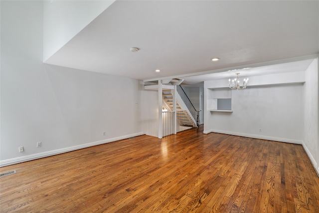 unfurnished living room featuring hardwood / wood-style flooring and an inviting chandelier